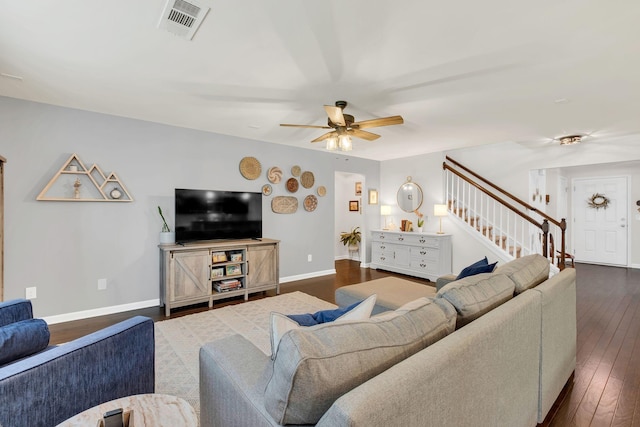 living room with visible vents, stairs, dark wood-style flooring, baseboards, and ceiling fan