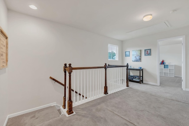 hallway with carpet flooring, baseboards, an upstairs landing, and attic access