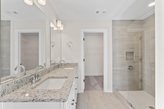 full bathroom with visible vents, a sink, a walk in closet, and a shower stall