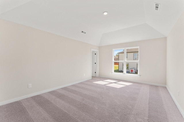 unfurnished room with carpet floors, baseboards, vaulted ceiling, and visible vents