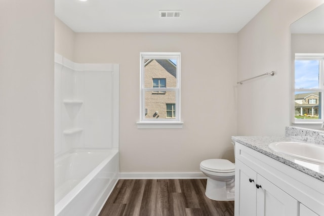 bathroom featuring baseboards, toilet, wood finished floors, and a wealth of natural light