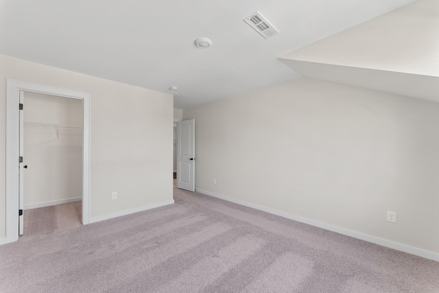 unfurnished bedroom featuring light colored carpet, baseboards, visible vents, and a spacious closet