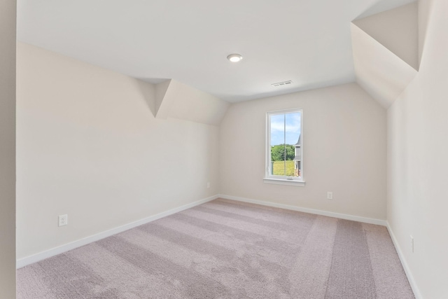 additional living space featuring baseboards, visible vents, light colored carpet, and lofted ceiling