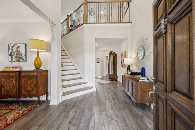 entrance foyer featuring baseboards, ornamental molding, wood finished floors, and stairway