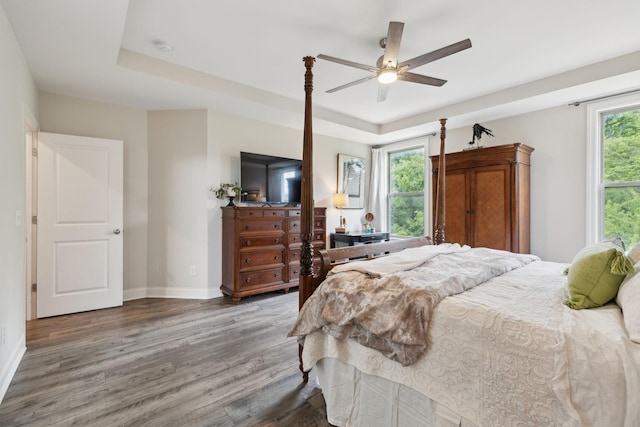bedroom with baseboards, multiple windows, and wood finished floors