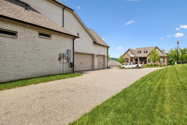 view of home's exterior featuring a garage, a lawn, driveway, and brick siding