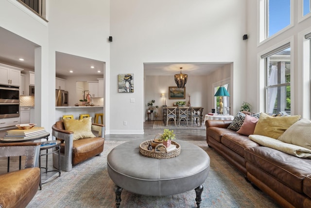 living area featuring a high ceiling, a chandelier, dark wood finished floors, recessed lighting, and baseboards