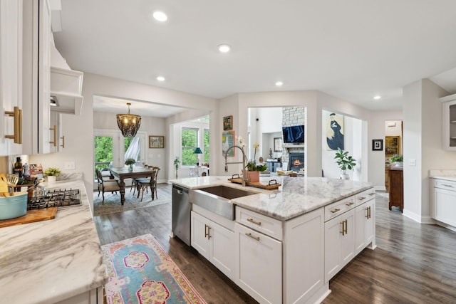 kitchen with white cabinets, light stone counters, a sink, and dishwasher