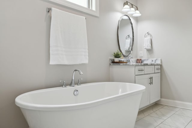 bathroom featuring vanity, baseboards, marble finish floor, and a freestanding bath