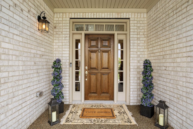 entrance to property with a porch and brick siding
