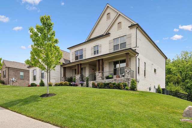 view of front of home with fence, covered porch, a front lawn, and brick siding