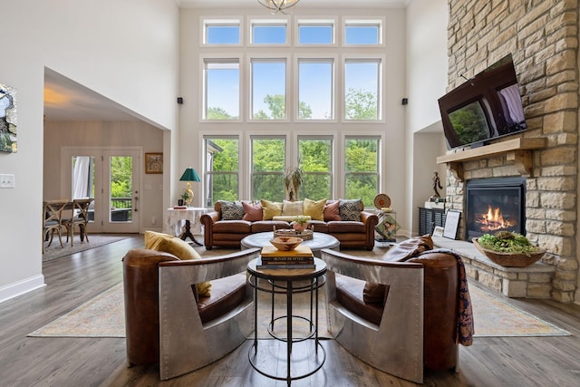 living area featuring baseboards, a high ceiling, a fireplace, and wood finished floors