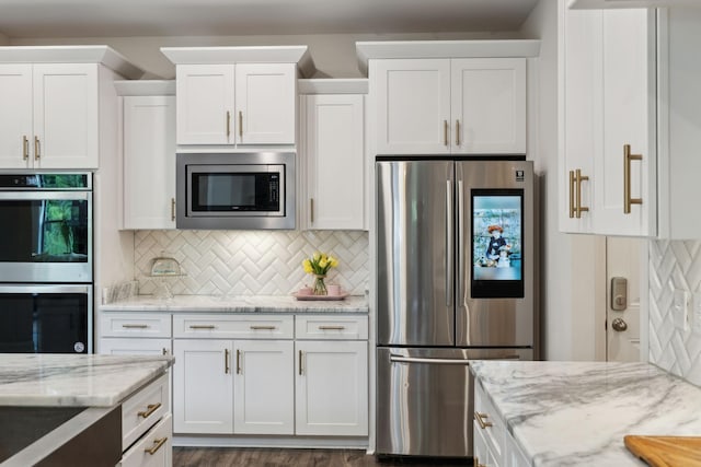 kitchen with light stone counters, appliances with stainless steel finishes, backsplash, and white cabinets