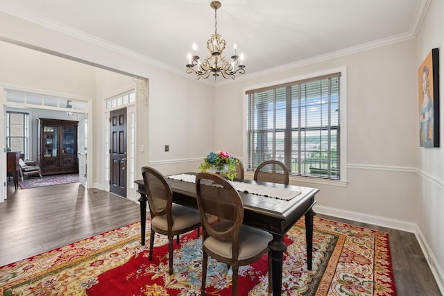 dining room with baseboards, ornamental molding, wood finished floors, and a notable chandelier