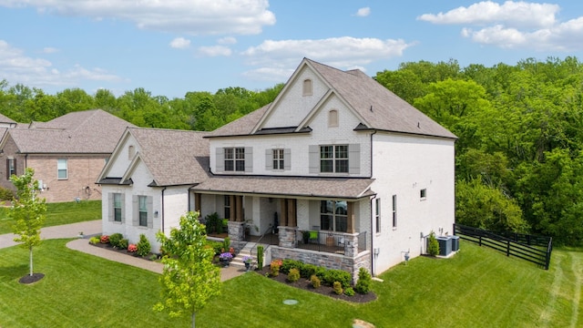 view of front of property featuring covered porch, brick siding, fence, and a front lawn