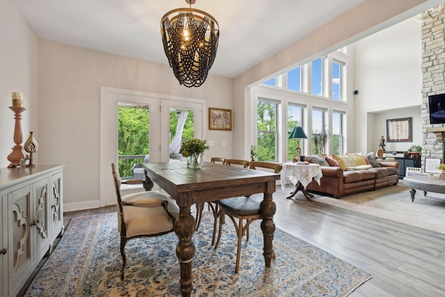 dining space with a stone fireplace, wood finished floors, and a chandelier