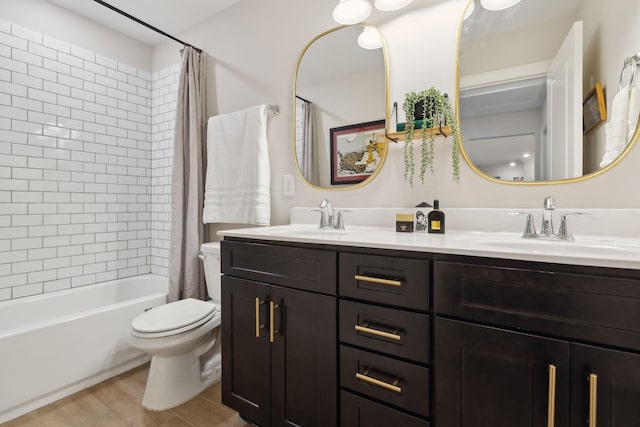full bathroom featuring a sink, double vanity, toilet, and wood finished floors