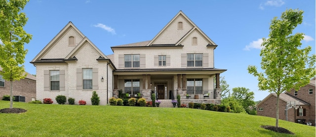 craftsman inspired home with central air condition unit, a porch, a front lawn, and brick siding