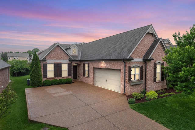traditional-style house with an attached garage, a front lawn, brick siding, and driveway