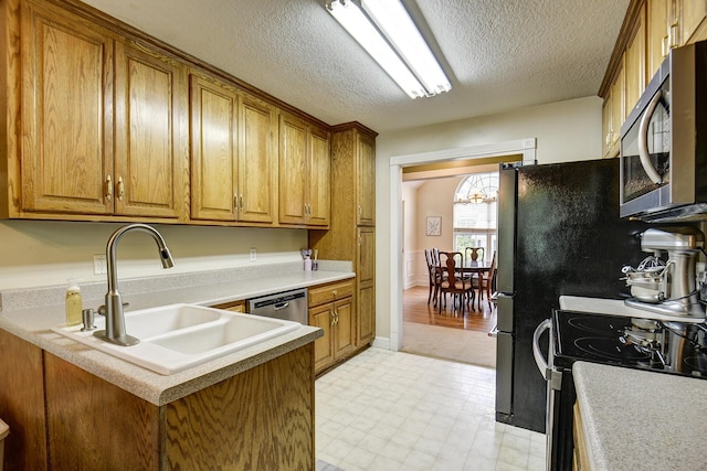 kitchen featuring stainless steel appliances, brown cabinetry, a sink, and light floors