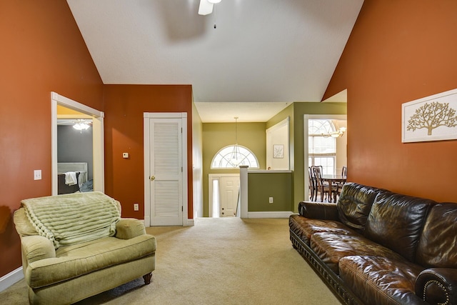 living area featuring baseboards, ceiling fan with notable chandelier, high vaulted ceiling, and light colored carpet