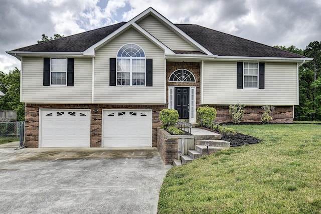 split foyer home featuring an attached garage, a front yard, driveway, and brick siding