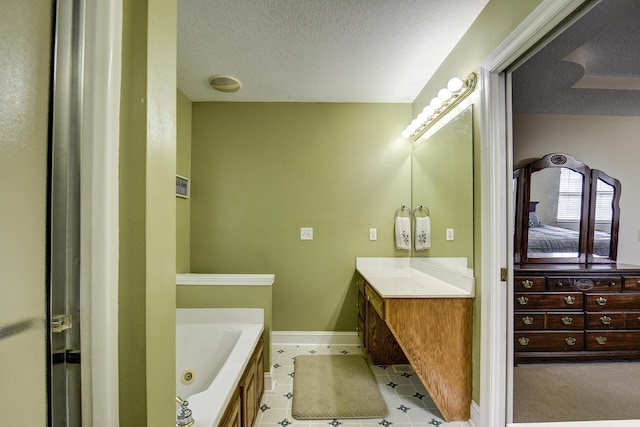 bathroom with a jetted tub, vanity, tile patterned floors, and a textured ceiling