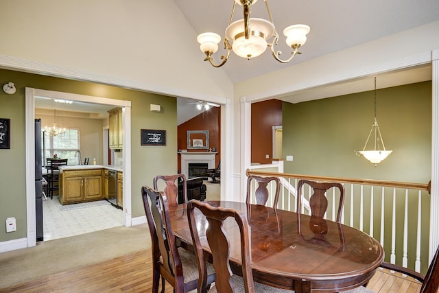 dining room featuring baseboards, light wood finished floors, lofted ceiling, and a fireplace