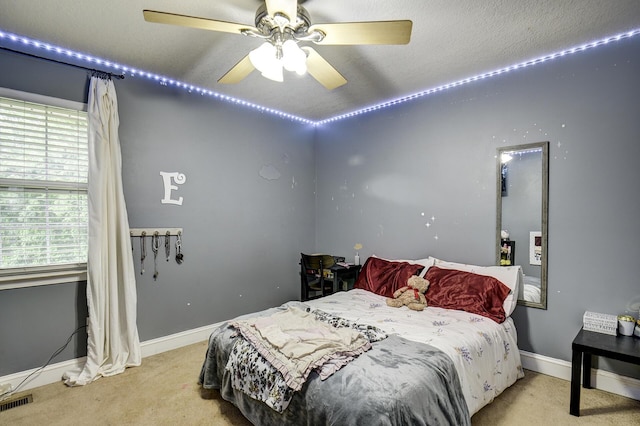 carpeted bedroom with a ceiling fan, baseboards, and visible vents