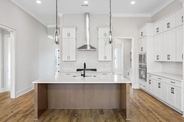 kitchen featuring crown molding, light countertops, appliances with stainless steel finishes, and wall chimney range hood
