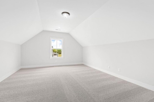 additional living space with carpet flooring, baseboards, and vaulted ceiling