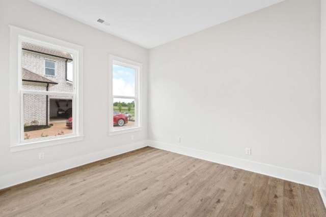 spare room with baseboards, wood finished floors, and visible vents