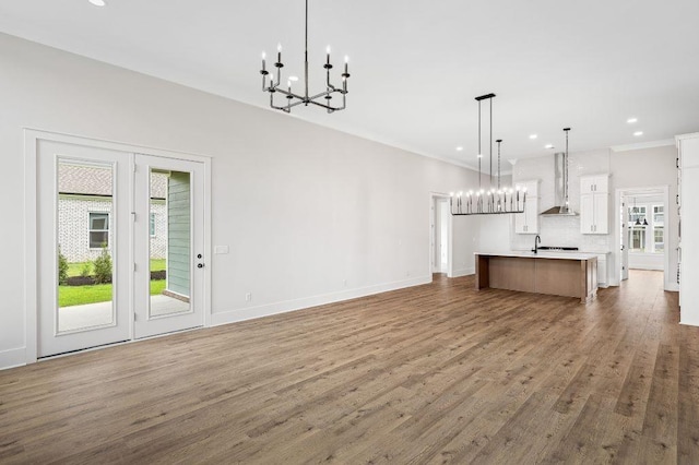 unfurnished living room with plenty of natural light, recessed lighting, wood finished floors, and a notable chandelier