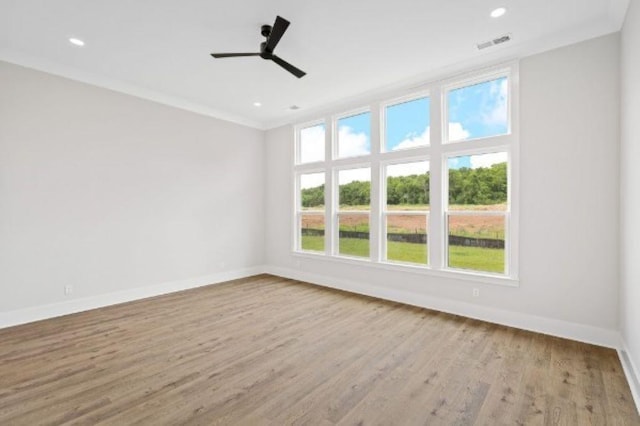 unfurnished room with crown molding, visible vents, wood finished floors, baseboards, and ceiling fan