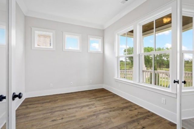 empty room with baseboards, dark wood-style flooring, and crown molding