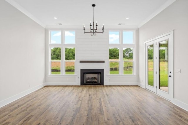 unfurnished living room featuring a fireplace, a chandelier, baseboards, wood finished floors, and ornamental molding