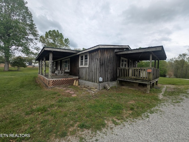 view of side of property featuring a lawn, board and batten siding, and a porch
