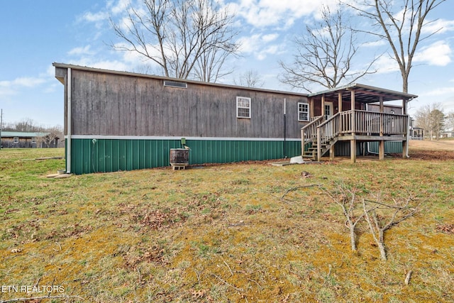 rear view of property with a yard, a deck, and stairs