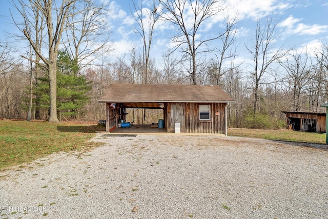 view of outdoor structure with driveway, an outbuilding, and a carport