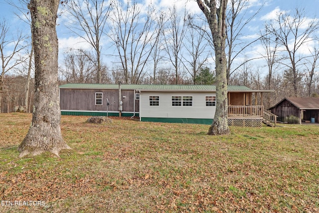 manufactured / mobile home with a wooden deck, metal roof, and a front lawn