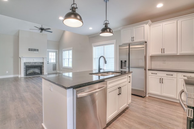 kitchen featuring a sink, light wood-style floors, stainless steel appliances, a ceiling fan, and vaulted ceiling