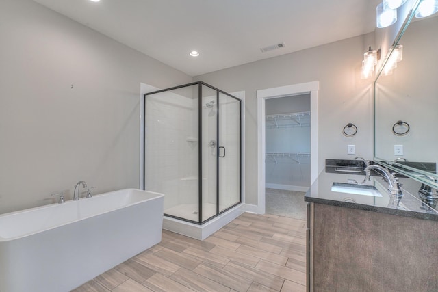 bathroom featuring double vanity, visible vents, a shower stall, a sink, and a soaking tub