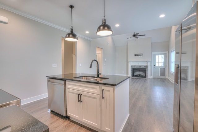 kitchen featuring a ceiling fan, a fireplace, a sink, white cabinets, and stainless steel appliances