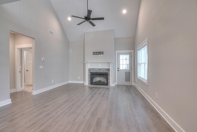 unfurnished living room with visible vents, a fireplace, baseboards, ceiling fan, and high vaulted ceiling