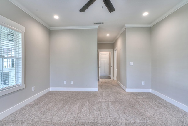 spare room with a ceiling fan, a healthy amount of sunlight, light carpet, and ornamental molding