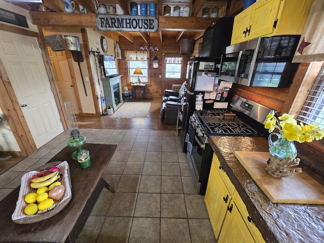 kitchen with wooden walls, stainless steel appliances, and dark tile patterned flooring