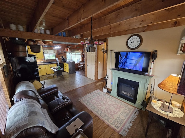 living room featuring beamed ceiling, a glass covered fireplace, wooden ceiling, and wood finished floors
