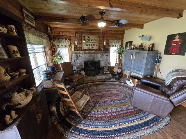 living room featuring wood finished floors, a fireplace, beamed ceiling, ceiling fan, and wooden ceiling
