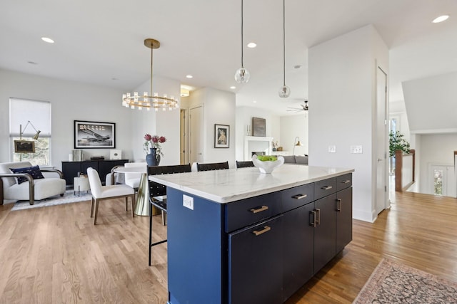 kitchen featuring open floor plan, a kitchen bar, light wood-type flooring, a center island, and hanging light fixtures