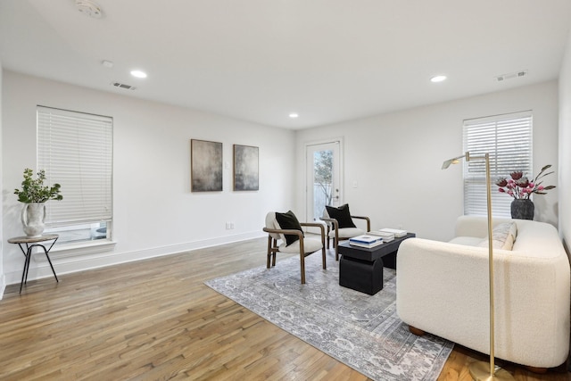 living area with baseboards, visible vents, and light wood-style floors